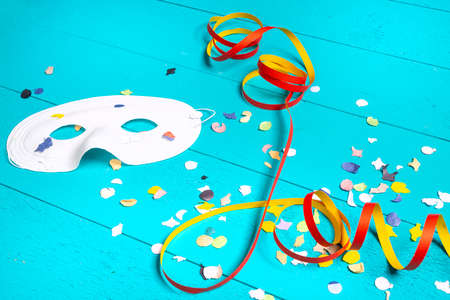 masks, confetti and streamers on a colorful carnival tableの写真素材