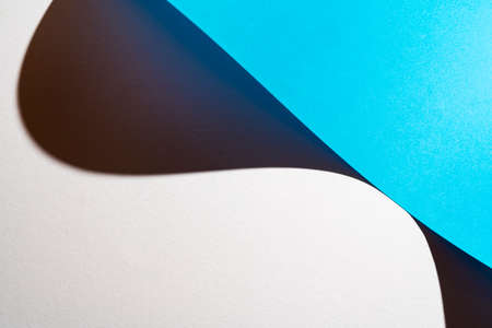 the shadow formed by a sheet of light blue paper folded on the white surfaceの写真素材