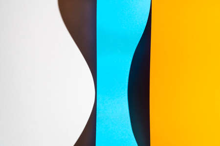 sheets of folded colored paper with a shadow formed on the surfaceの写真素材