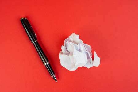 a pen and a crumpled sheet of paperの写真素材
