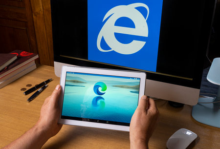 Udine, Italy, August 2021. the symbol of the new Microsoft Edge browser on a tablet screen with the symbol of Internet Explorer on a computer screen.のeditorial素材