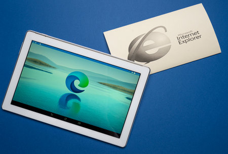 Udine, Italy, August 2021. the symbol of the new Microsoft Edge browser on a tablet screen with the symbol of Internet Explorer in black and white on a sheet of paperのeditorial素材