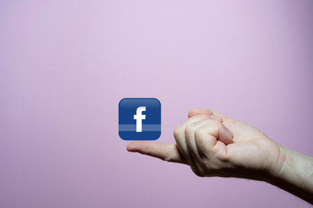 the Facebook symbol in the tip of a finger with the blue background