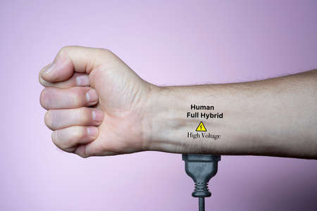 a man connected with a plug to the electric power in his armの写真素材