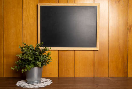 an empty blackboard hanging on a wooden wall