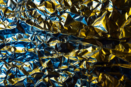 crumpled foil background illuminated with colored lightsの写真素材
