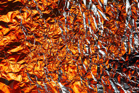 crumpled foil background illuminated with colored lightsの写真素材
