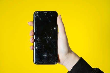 A cellphone with a broken screen in handの写真素材