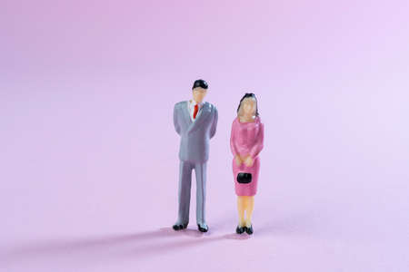 a couple of miniature people together on a colored surfaceの写真素材
