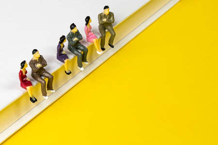 a row of miniature models sitting in a row on the edge of a bookの写真素材