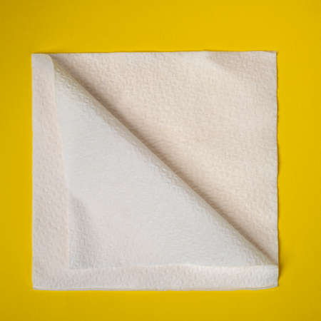 a paper napkin folded diagonally on a yellow surfaceの写真素材