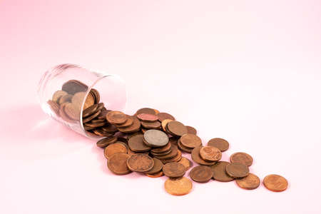 the coins spilled from a glass between some Euro banknotes