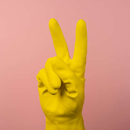 the V gesture made with a hand wearing a yellow rubber gloveの写真素材