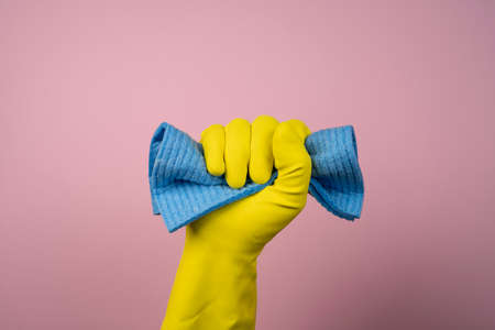 a hand with a yellow rubber glove holds a cleaning spongeの写真素材
