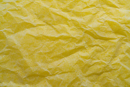 the reflections of light on a sheet of crumpled paper on a yellow surface