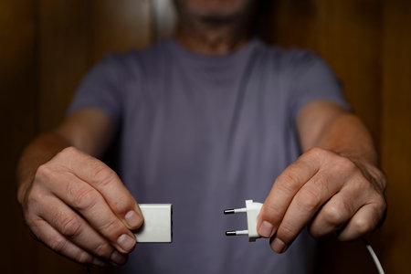 a man while disconnecting an electrical socket from the plugの写真素材