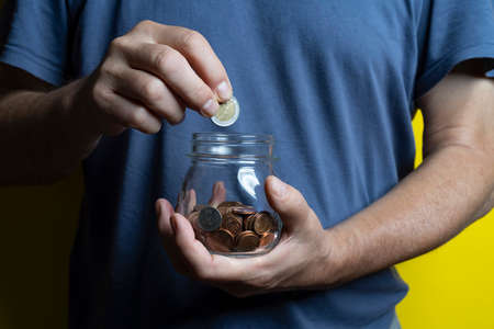 a man saves by collecting coins in a glass jar