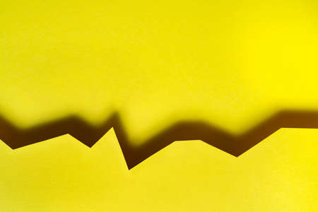 a yellow background formed with the shadow of a cut cardの写真素材