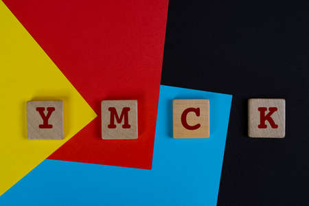 YMCK color space. The letters Y, M, C and K on a wooden towels over a yellow, red, cyan and black backgroundの写真素材