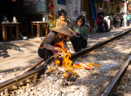 Hanoi, Vietnam. Jnauary 2023. A woman burning tiá»n Ã¢m phá»§, votive offerings for ancestors along the train tracks in front of her home in the old quarter of the cityのeditorial素材