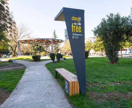 Tirana, Albania. March 2023. Benches with sockets for free mobile phone charging in a city park.のeditorial素材