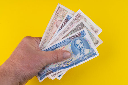 some Vietnamese Dong banknotes on a yellow surfaceの写真素材