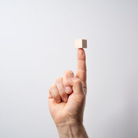 a wooden cube on the tip of the finger with a white backgroundの写真素材