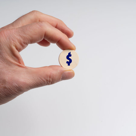 a wooden disk with a dollar symbol held by a male hand on a transparent background