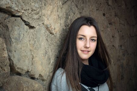 The nice young beautiful girl was photographed on walk at a wallの写真素材