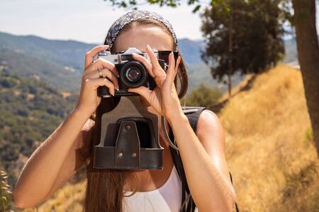 the beautiful girl the traveler with the camera has been photographed on walk in mountainsの写真素材