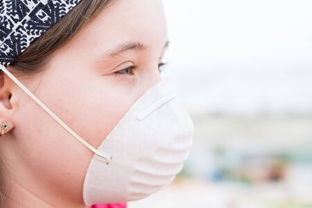 Beautiful girl in protective mask was photographed on the roof of the houseの写真素材