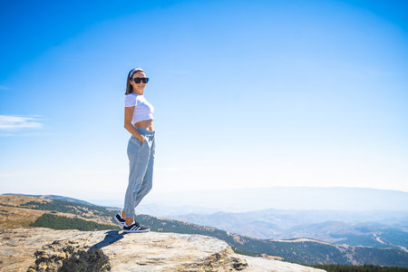 Young woman standing on top of a mountain and enjoying the view.の写真素材