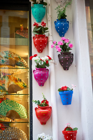 Colorful ceramic pots with flowers hanging on the wall of a shop windowの写真素材
