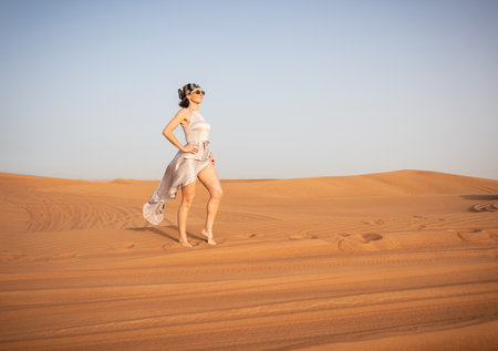 Beautiful girls in a beautiful flowing dress in desert conditionの写真素材