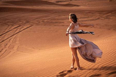 Beautiful girls in a beautiful flowing dress in desert conditionの写真素材