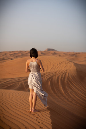 Beautiful girls in a beautiful flowing dress in desert conditionの写真素材