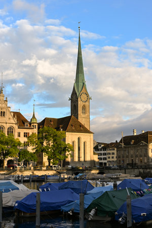 Scenic view of Limmat river in ZÃ¼rich with boats, reflections, and FraumÃ¼nster church under a colourful morning skyの写真素材