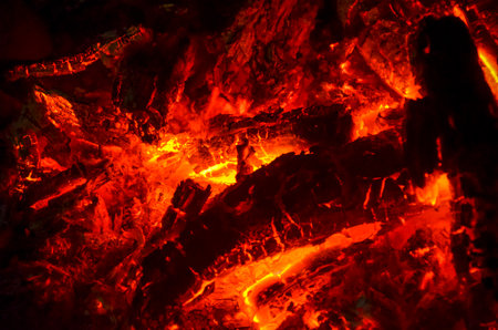 Close-up of glowing embers and burning wood, radiating intense heat and vivid orange lightの写真素材