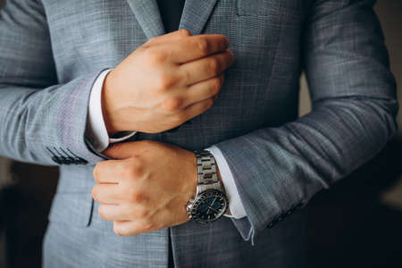 people, business, fashion and clothing concept - close up of man dressing up and fastening buttons on shirt at home.の写真素材