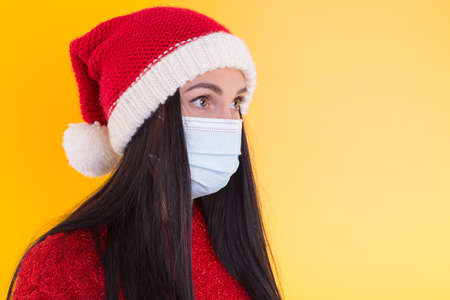 Young woman with medical mask and santa hat on white background. Christmas on quarantine.の写真素材