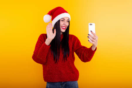 Christmas online congratulations. woman in Santa hat using mobile tablet for video call friends and parents.の写真素材