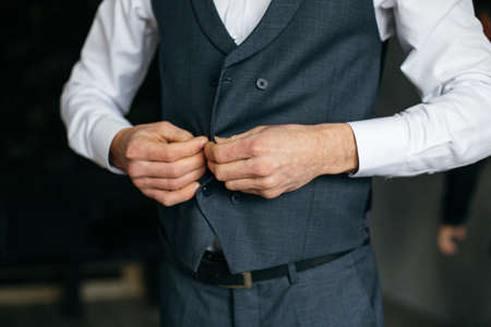 Cheerful young man in a gray suit touches a jacketの写真素材