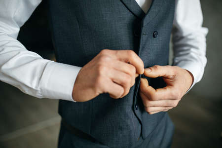Cheerful young man in a gray suit touches a jacketの写真素材