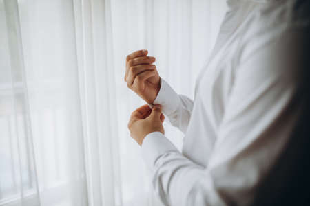 man buttons shirt, a man in a white shirt, hands of a man close-up, businessman puts on a suit