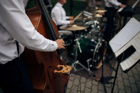 Jazz band performs at the club. a man plays the double bass with a band .