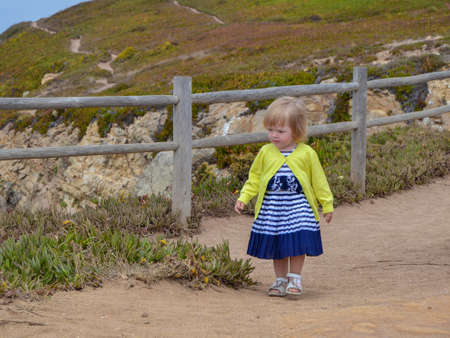 Little girl walks along the fence at Cape Cabo da Roca.