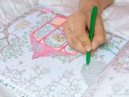 Female hand drawing with crayon in adult anti stress coloring closeup.の写真素材