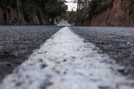 Road in low perspective from the asphalt with a car in the distanceの写真素材