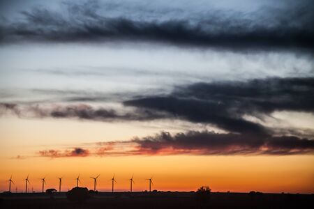 Sunset landscape at wind generators field with blue and orange sky