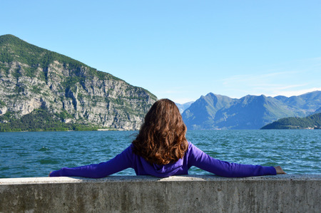 Young woman sitting on bench facing the lakeの写真素材